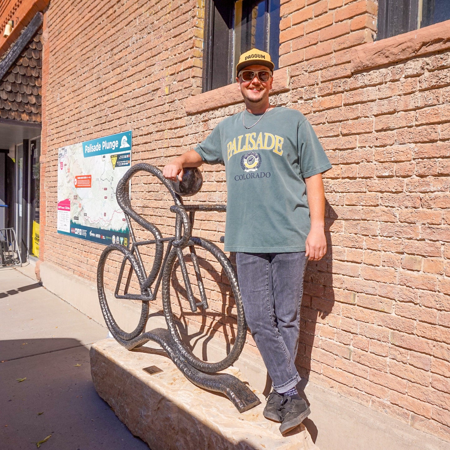 Person standing next to a bike rack on a sidewalk with a brick building in the background